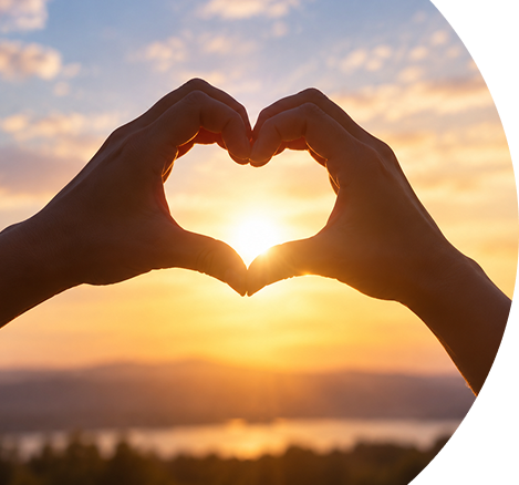 Hands forming a heart shape at sunset