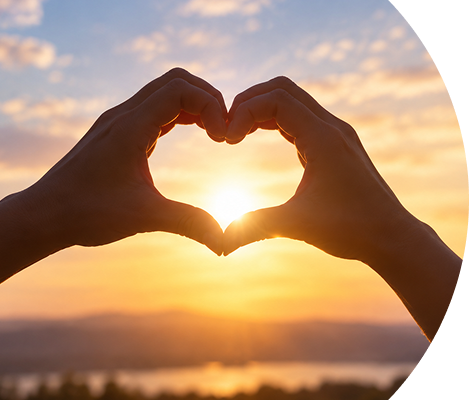 Hands forming a heart shape at sunset