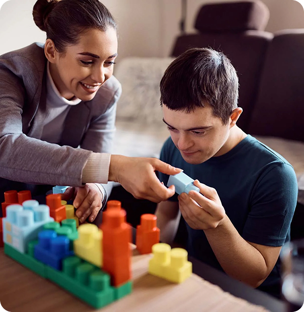 Young adult building with blocks alongside a support worker